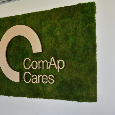 Originální mechová stěna s dřevěným logem firmy ComAp Cares